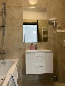 y baño con lavabo, bañera y espejo. en DEKO Apartments & Studios Near Palas Mall en Iaşi