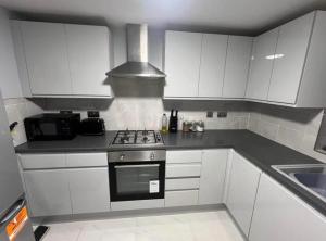 a kitchen with white cabinets and a stove top oven at Double Bedroom in London