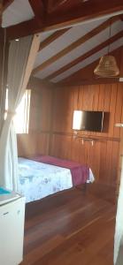 a bedroom with a bed and a tv on the wall at Encontro das Águas in Guarda do Embaú
