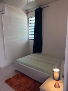 a small bedroom with a bed and a window at SIMPLISSIME T4 à KOUROU in Kourou