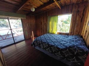 1 dormitorio con 1 cama en una cabaña con ventanas en grandes cabañas 2 en Pucón