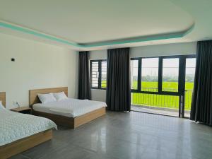 a bedroom with two beds and a large window at Ruby Motel Bà Rịa in Ba Ria