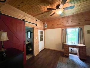 sala de estar con paredes de madera y ventilador de techo. en Quiet Retreat in Amish country, 