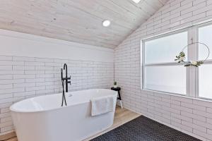uma casa de banho branca com uma banheira e uma janela em Midtown Masterpiece Whot Tub, Pets Welcome! em Tulsa