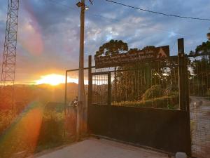 a gate with a rainbow in front of a sunset at Chalés Capivari Diamante in Campos do Jordão
