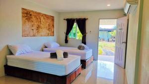 two beds in a room with a door to a yard at ปารมีฟาร์มสเตย์ in Ban Chao Nam