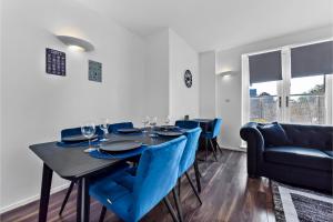 a dining room with a black table and blue chairs at Charming and Modern 2 BR Flat in London