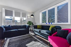 a living room with black leather furniture and windows at Charming and Modern 2 BR Flat in London