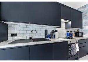 a kitchen with black cabinets and a sink at Three Bedroom Home - Perfect for Large Groups in London +25 photos