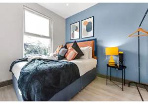 a bedroom with a bed with a blue wall at Three Bedroom Home - Perfect for Large Groups in London
