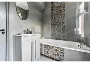 a bathroom with a tub and a sink and a mirror at Three Bedroom Home - Perfect for Large Groups in London