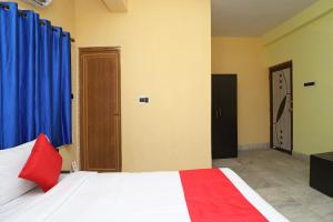 um quarto com uma cama com uma almofada vermelha e cortinas azuis em OYO Maa Tara Guest House Near Acropolis Mall em Jādabpur