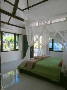 a bedroom with a green bed with a canopy at Gili Hideaway in Gili Trawangan