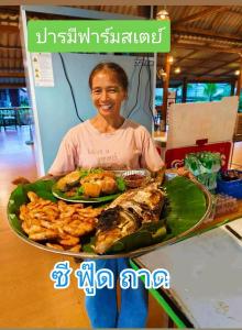 a woman holding a tray of food on a plate at ปารมีฟาร์มสเตย์ in Ban Chao Nam