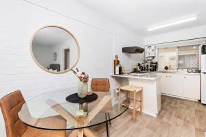 a white kitchen with a glass table and a mirror at Urban Chic Studio by 'the Strip' in Perth +10 photos