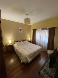 ein Schlafzimmer mit einem Bett, zwei Tischen und einem Fenster in der Unterkunft Tu casa en parque in Necochea