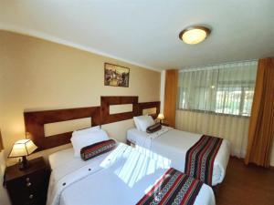 a hotel room with two beds and a window at Hotel Humantay Lodge Ollantaytambo in Ollantaytambo