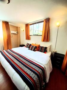 a bedroom with a large bed with orange curtains at Hotel Humantay Lodge Ollantaytambo in Ollantaytambo