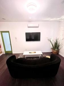 a living room with a black couch and a tv at Beautiful 1 BR Art DECO Inspired in Philadelphia