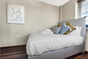 - une chambre avec un grand lit blanc et des oreillers dans l'établissement Gorgeous Flat, Perfect for Family/Large Group, à Londres