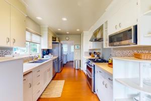 a large kitchen with white cabinets and a wooden floor at Butterfly Landing in Pacific Grove