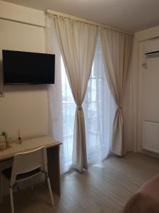 um quarto com uma secretária e uma janela com cortinas em Masha em Mamaia Nord – Năvodari