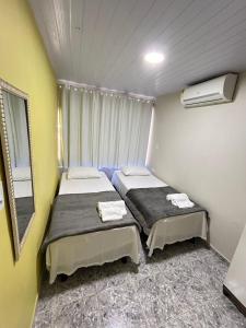 - 2 lits dans une petite chambre avec fenêtre dans l'établissement Suites Mar Azul, à São José da Coroa Grande