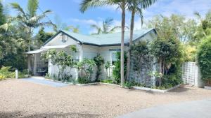 a white house with palm trees in front of it at The Boathouse a 3 Bedroom House in Narooma