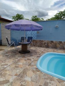 einen Tisch und Stühle mit einem Sonnenschirm neben dem Pool in der Unterkunft Casa de campo Maria&Maria próximo a cidade de Juiz de Fora MG in Juiz de Fora