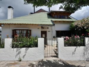 una casa blanca con una valla y flores en pampa en San Carlos de Bariloche