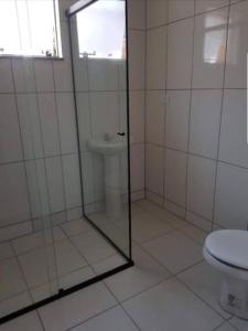 La salle de bains est pourvue d'une douche en verre et de toilettes. dans l'établissement Apartamentos na Quadra do Mar, à Guaratuba