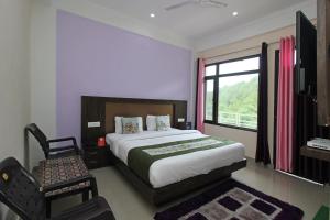 a bedroom with a bed and a chair and a window at OYO Hotel Chandni in Dharmsāla