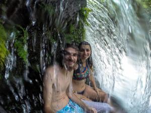a man and a woman sitting in front of a waterfall at Ali Atrás in Macaé