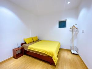 a bedroom with a bed with a yellow blanket at Lá Homestay Apartment in Long Xuyên