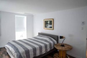 Dormitorio blanco con cama y mesa en Bel appartement au centre-ville, en Granby