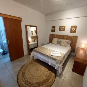 Dormitorio con cama con espejo y alfombra en Mala & Tudo Pousada, en Torres