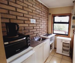 a kitchen with a sink and a brick wall at Cumbres Nevadas in Coihaique