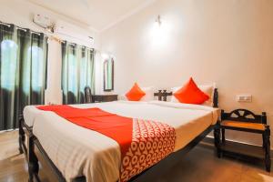 um quarto com uma cama grande com lençóis laranja e branco em OYO La Petite Near Dabolim Airport em Chicolna
