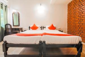 a bedroom with a large bed with orange pillows at OYO La Petite Near Dabolim Airport in Chicolna