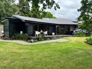 a black house with a table and chairs in a yard at Beluga - Self contained accomodation Kerikeri in Kerikeri