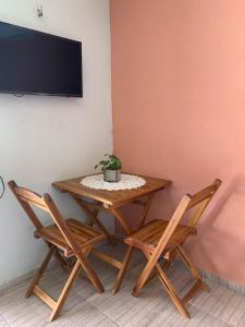 uma mesa com duas cadeiras e uma televisão na parede em Suíte Nativa - Flecheiras em Flecheiras