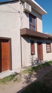 a white house with a door and a balcony at Casa festival Jesús María in Colonia Caroya