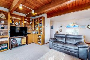 a living room with a leather couch and a flat screen tv at Rascals Oceanfront Retreat in Florence