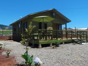 a small cabin with a large green umbrella at Cabañas en Chovellén, Pelluhue. in De Cauquenes