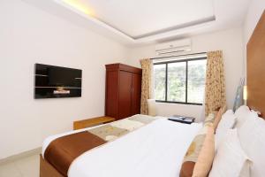 een slaapkamer met een groot bed en een televisie bij Super Capital O Hotel Dona Castle in Kollam