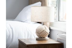 a lamp on a wooden table next to a bed at Lovely Home - Park Views & Ideal Transport Links in London