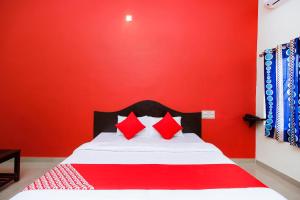 Un dormitorio con una pared roja y una cama con almohadas rojas. en Hotel Aljemin en Kanyakumari