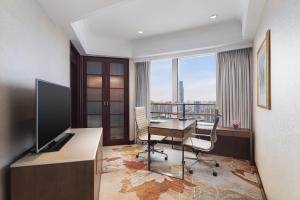 a room with a desk with a television and a table with chairs at Radisson Blu Hotel Shanghai New World in Shanghai