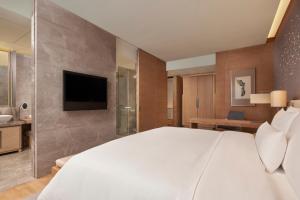 a bedroom with a large white bed and a television at The Westin Chongqing Liberation Square in Chongqing