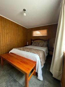 a bedroom with a bed and a wooden wall at Casa Lican Ray in Licán Ray